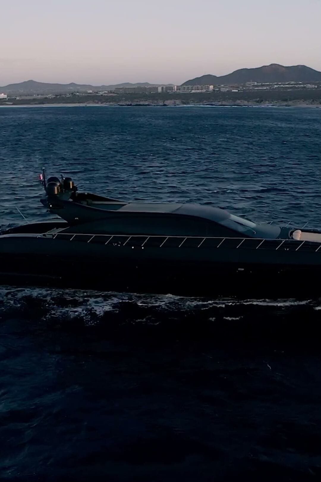 Neoprene, a 108 ft Overmarine superyacht, cruising past the Cabo San Lucas coastline at twilight